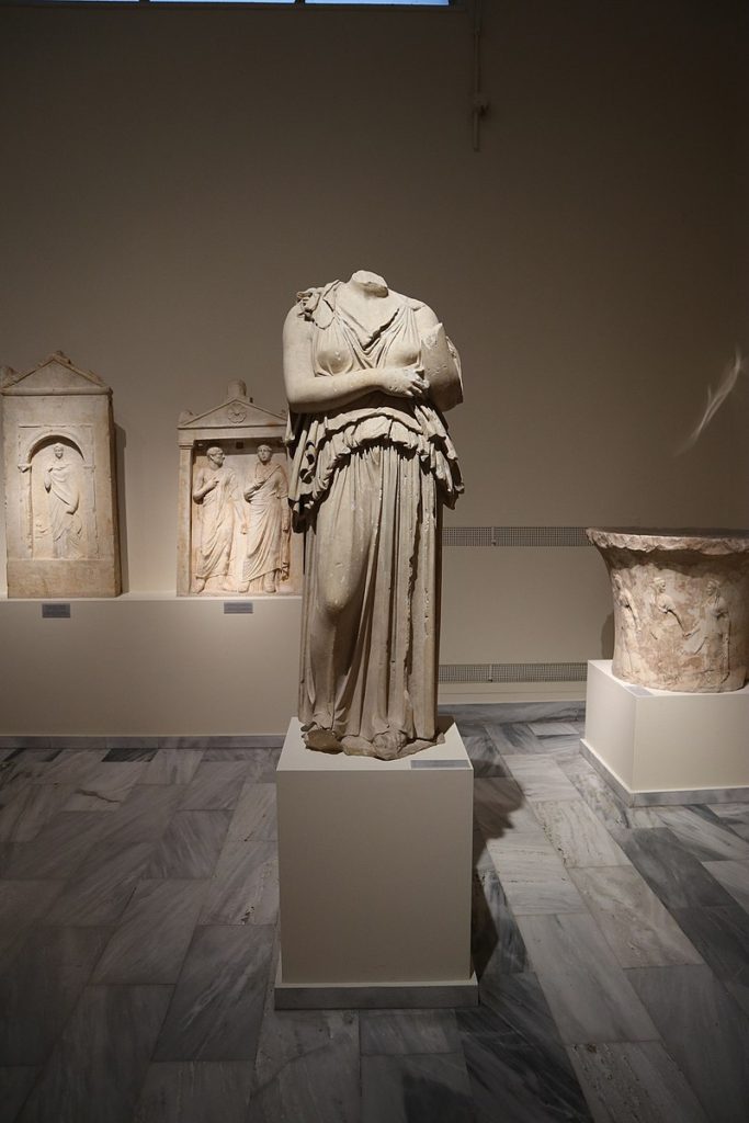 image of statue of a woman (statue is broken and does not have a head) wearing a peplos, statue is made of white marble